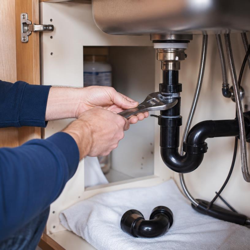 Plomero reparando la tubería debajo del fregadero de la cocina